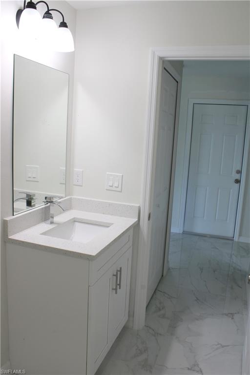 White vanity with a light-toned countertop, under-mount sink, and chrome faucet