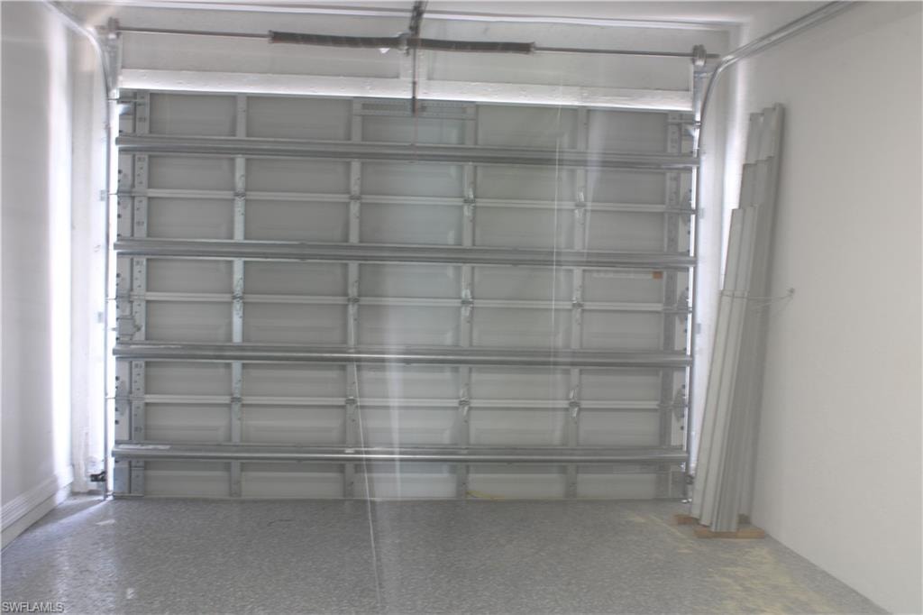 Garage interior featuring a sectional garage door, exposed metal track system, and a speckled epoxy floor finish