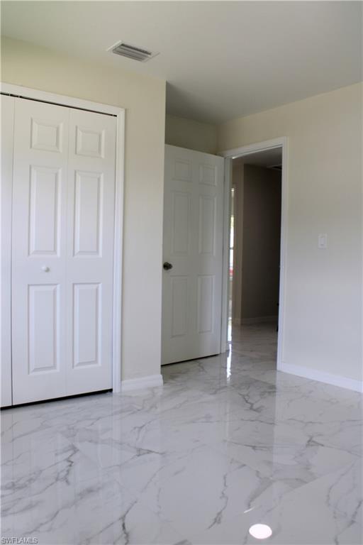 White paneled closet doors, high-gloss marble-look tile flooring, and light-toned wall finishes