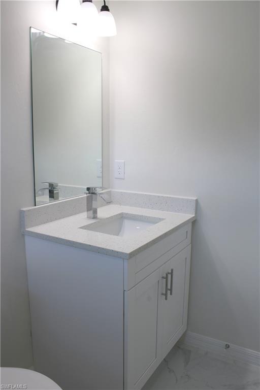 White vanity with a light-toned countertop, undermount sink, and polished chrome faucet