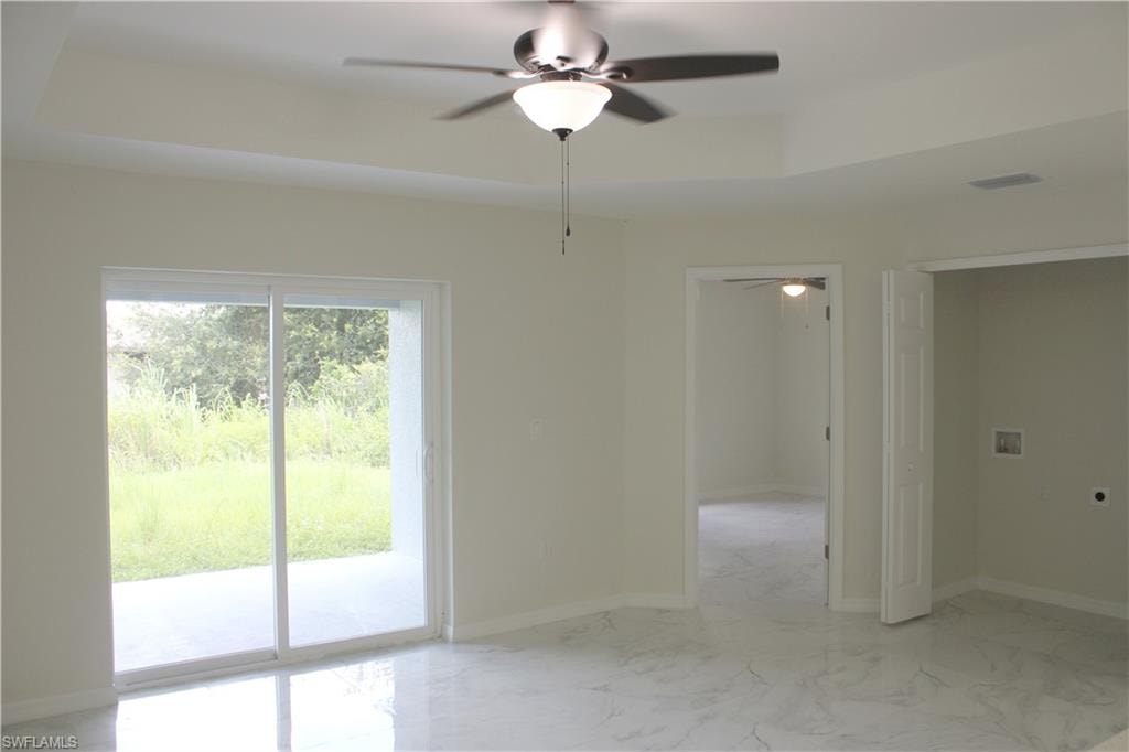 Tray ceiling with a ceiling fan, sliding glass doors to a concrete patio, tile flooring, and neutral wall paint