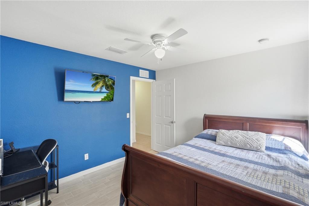 Guest bedroom featuring a white ceiling fan, recessed lighting, and light-toned wood-finish tile flooring