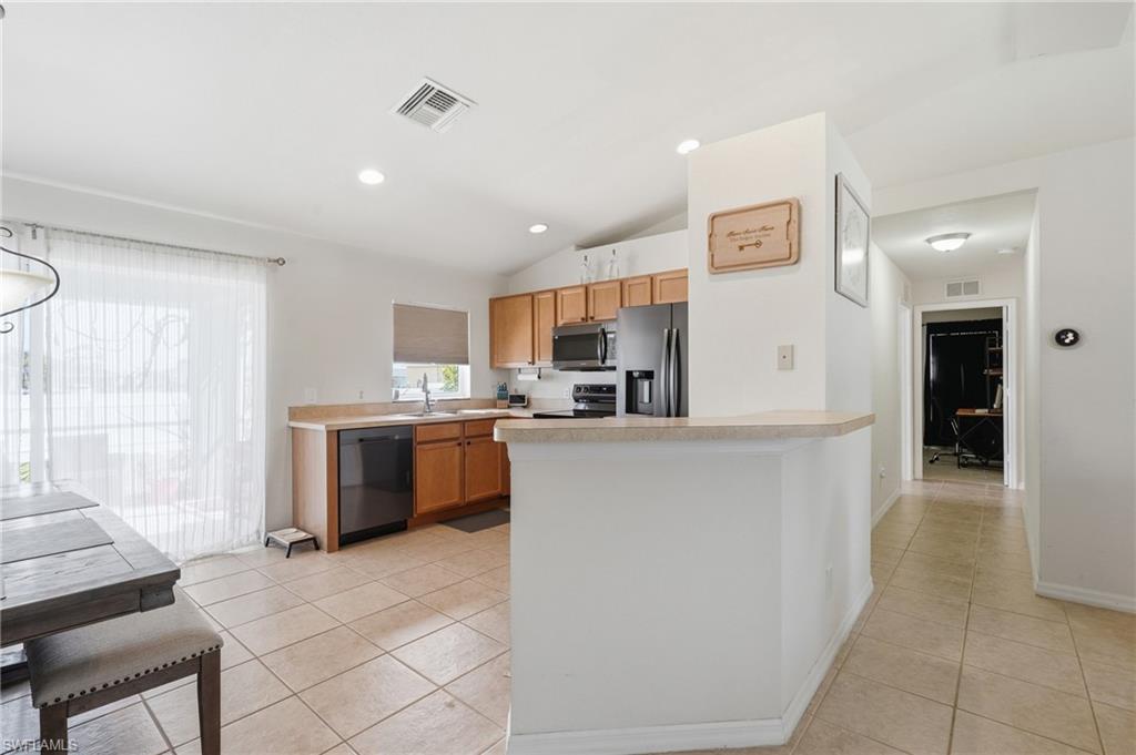 Kitchen featuring light-toned cabinetry, stainless steel appliances, and a breakfast bar