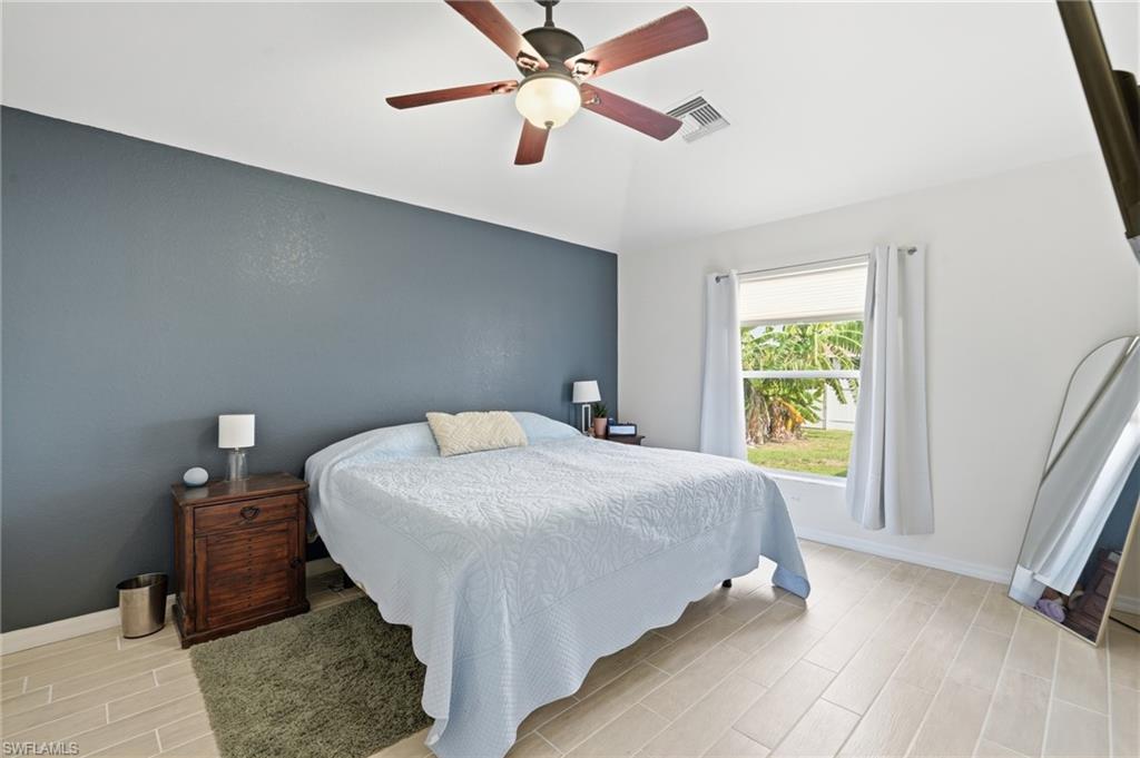 Ceiling fan, accent wall, light-toned tile flooring, and a large window