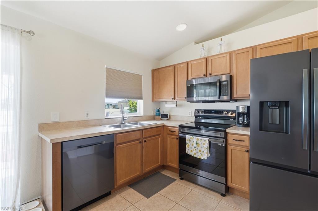 Light-toned cabinetry, tile flooring, and integrated appliances, including a microwave, range, and refrigerator