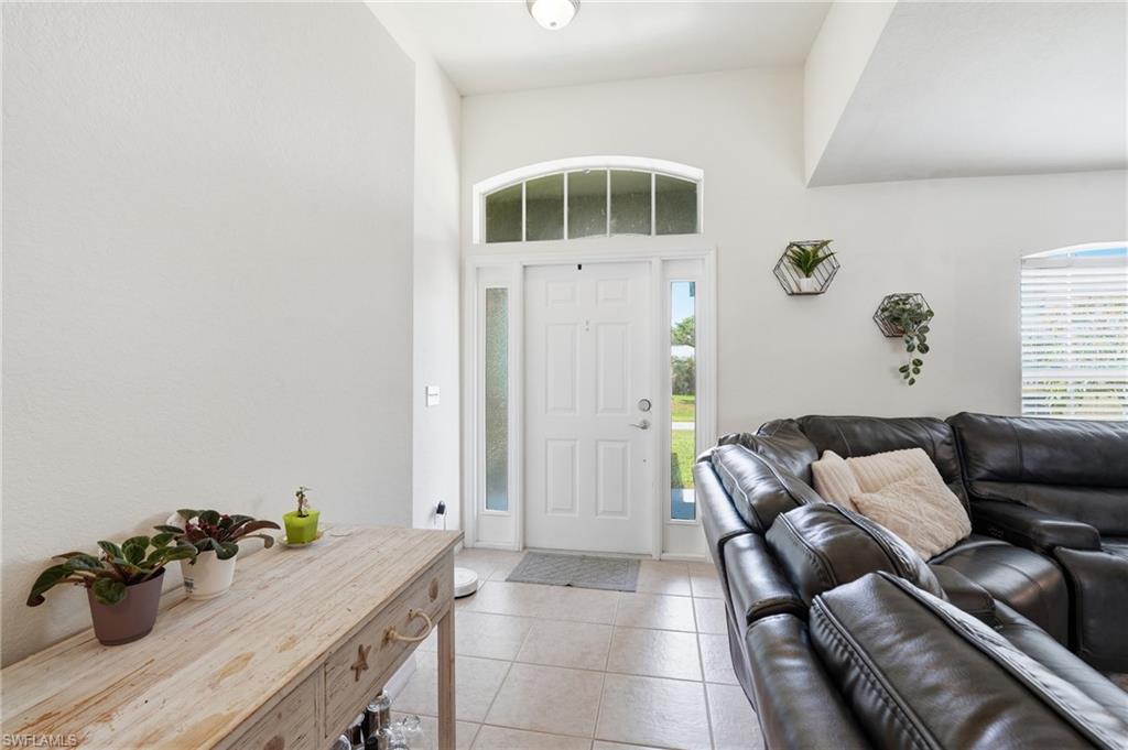 Entryway featuring a white paneled door with an arched transom window and sidelights, alongside tiled flooring