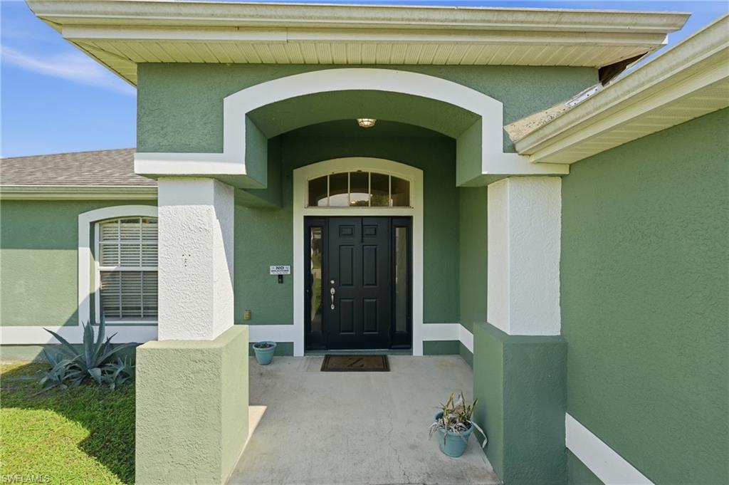 Stucco exterior featuring an arched portico entry with decorative columns and a dark paneled front door with an arched transom window