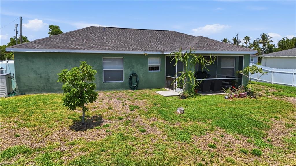 Stucco exterior with a shingled roof, screened patio, and privacy fencing