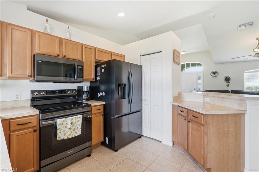 Kitchen featuring light-toned cabinetry, appliances, light-toned countertops, and tile flooring