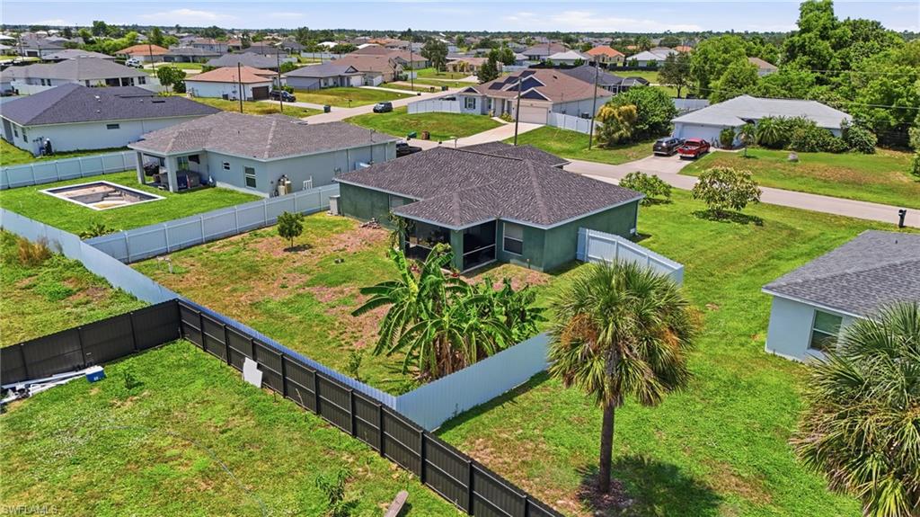 Fenced property with a screened-in patio, mature palm trees, and an established residential setting