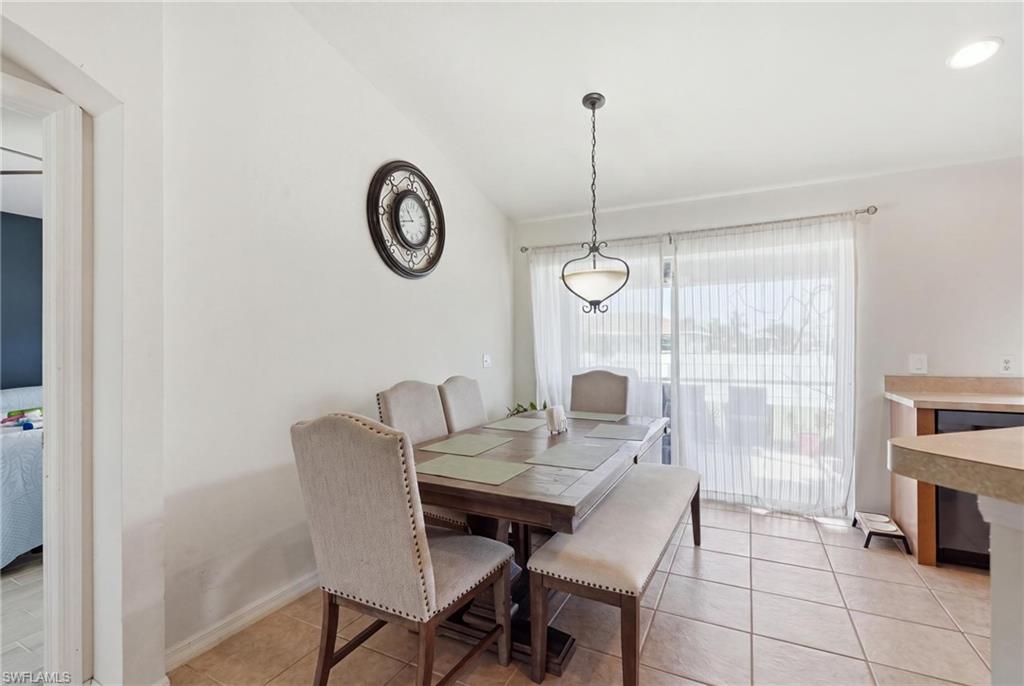 Vaulted ceiling, tile flooring, and a sliding glass door with sheer curtains
