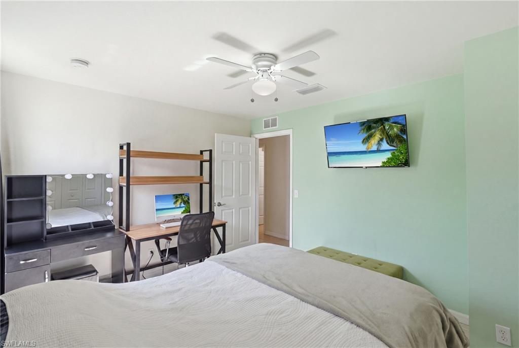 Guest bedroom, white ceiling fan with integrated lighting, wall-mounted television, and a paneled interior door