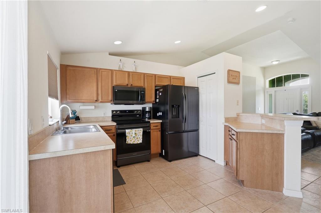 Kitchen featuring light toned cabinetry, solid surface countertops, tile flooring, and integrated appliances