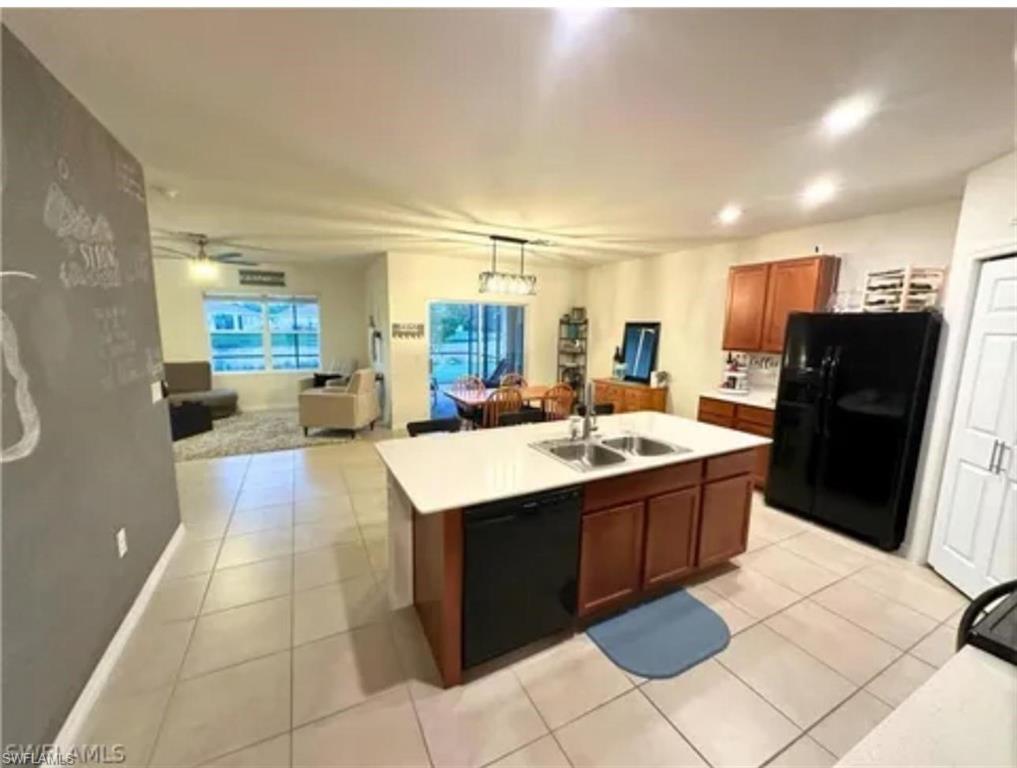 Kitchen featuring an island with dual sinks, overhead recessed lighting, tile flooring, and wood-finish cabinetry