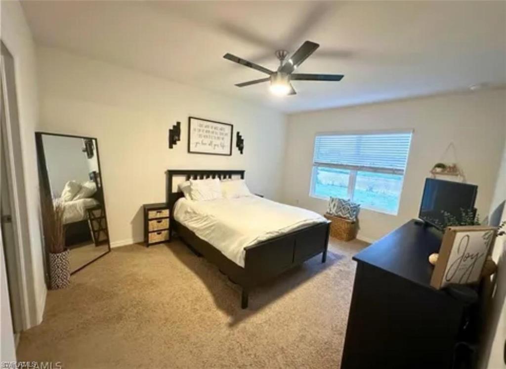 Carpeted flooring, ceiling fan with integrated lighting, window with blinds, and built-in closet