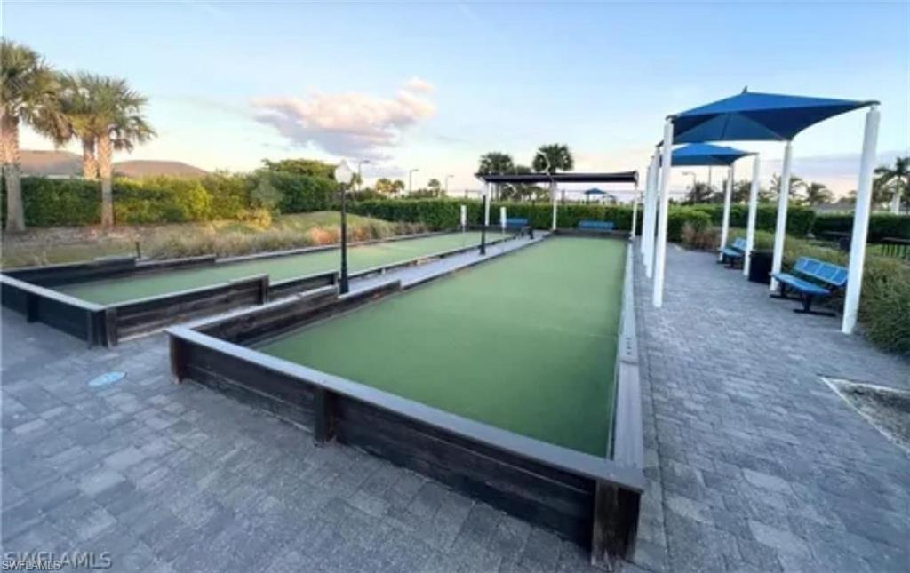 Paver walkway surrounding two bocce ball courts with shade structures and integrated seating