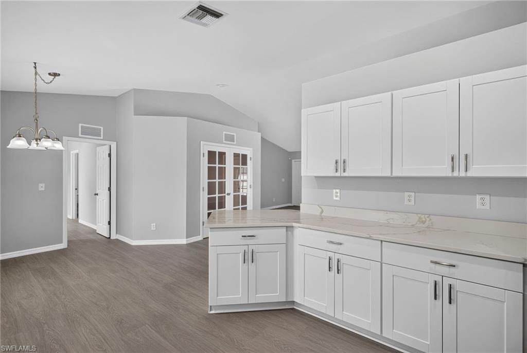 Kitchen facing dining room with minor bedrooms on left and den on right
