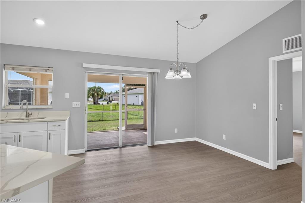 Dining room with kitchen to left, slider to lanai in middle, and minor bedrooms to the right