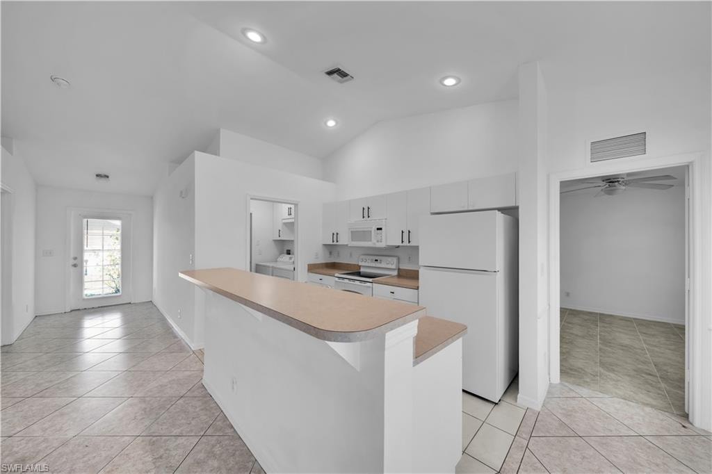 Kitchen featuring a breakfast bar, white cabinetry, and white appliances