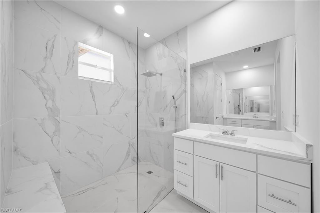 Spacious bathroom featuring a white vanity with an integrated sink and a large frameless mirror