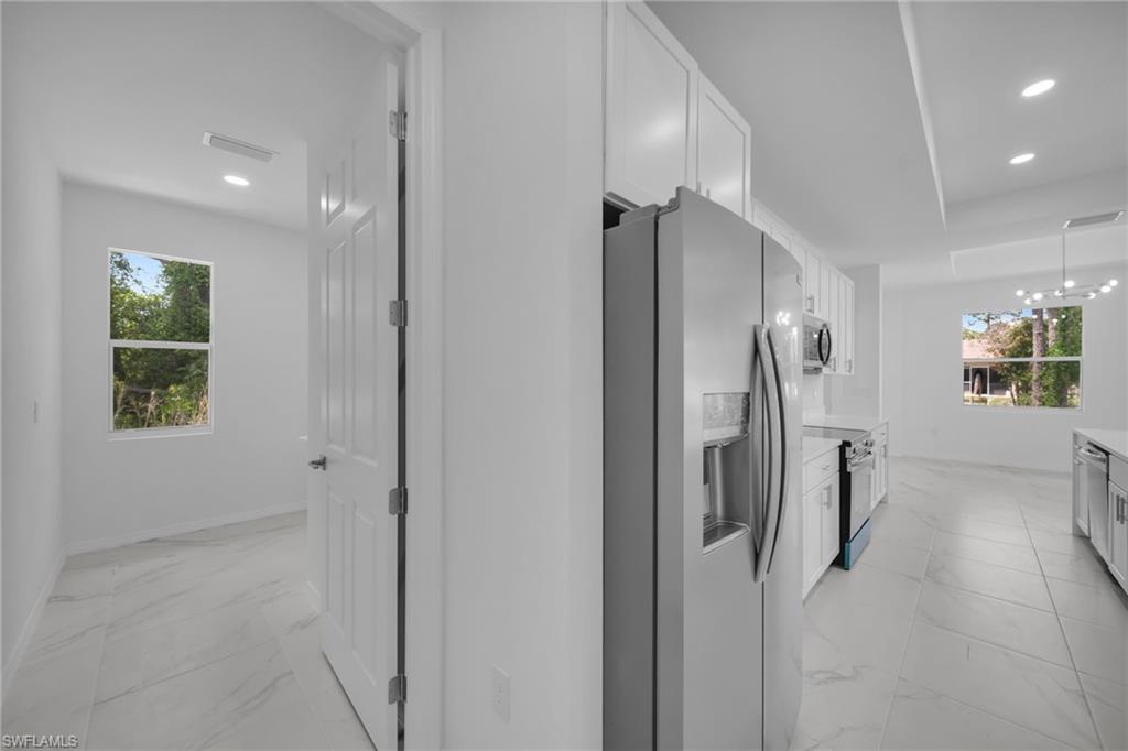 Open-concept kitchen featuring stainless steel appliances, white cabinetry, recessed lighting, and tile flooring