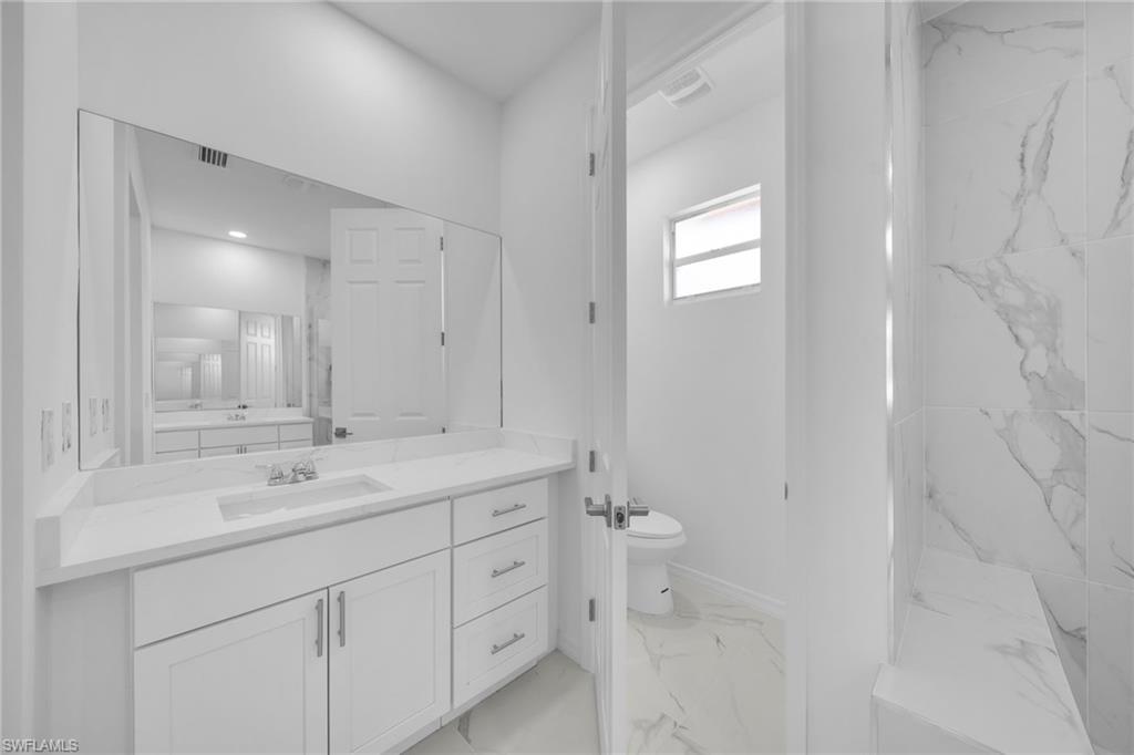 Bathroom featuring a white vanity with an undermount sink, a quartz-finish countertop, and ample storage cabinetry