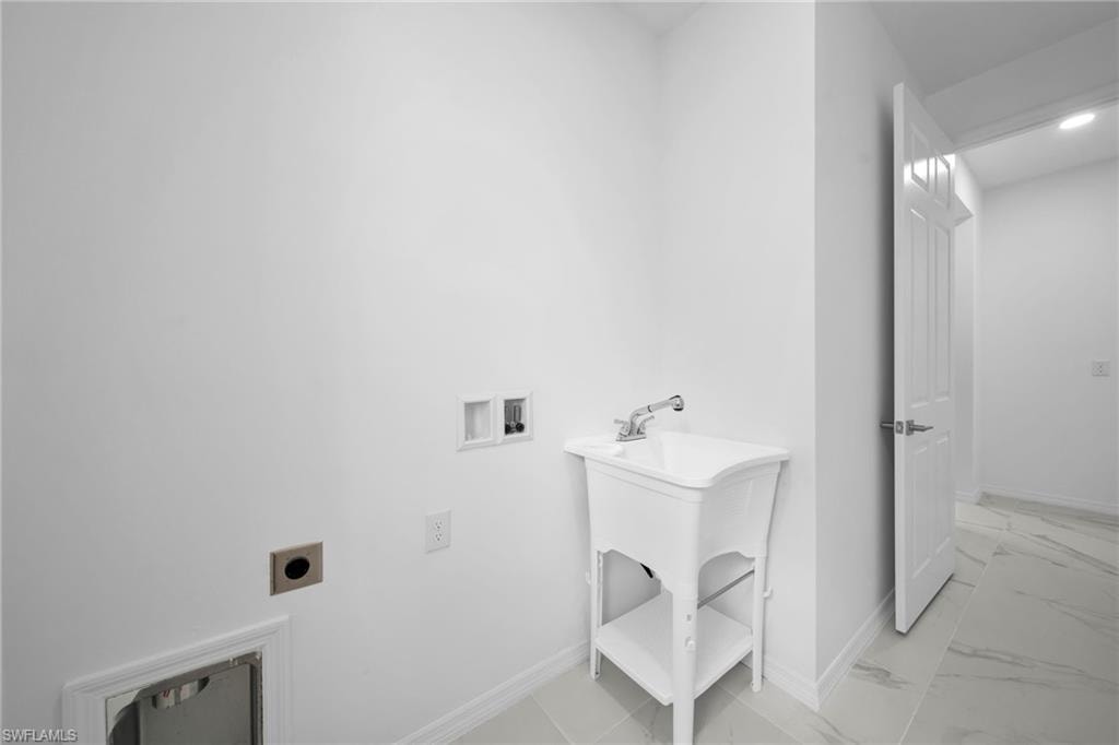 Utility room featuring a white laundry sink with a chrome faucet, white baseboards, and light-toned tile flooring