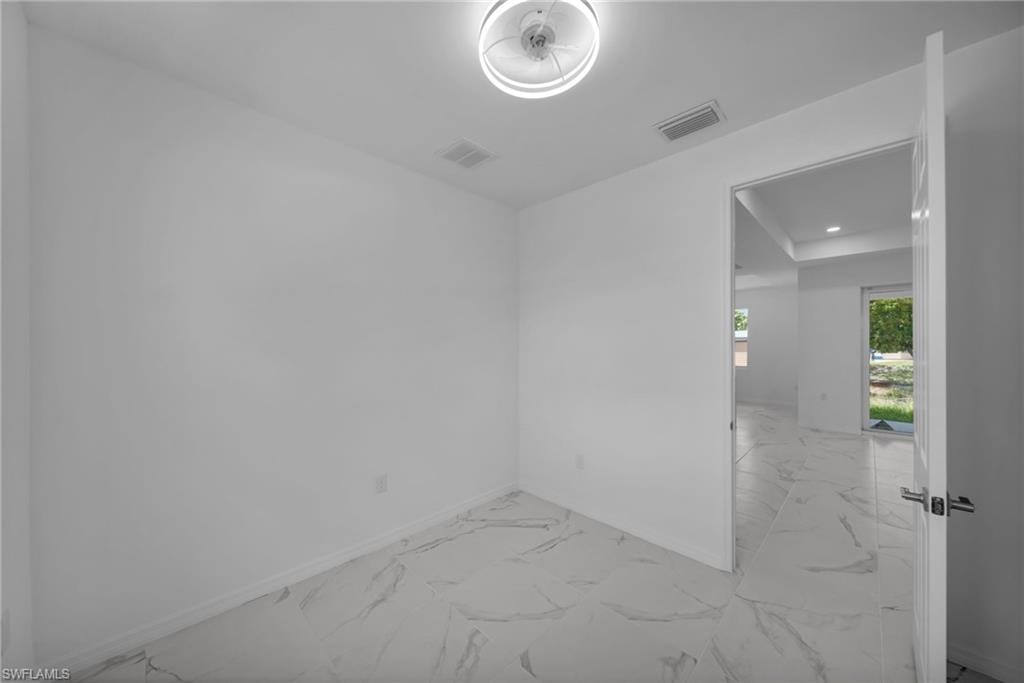 DEN !Bright white room featuring large format tile flooring with subtle veining, a modern flush-mount ceiling light, and white baseboards