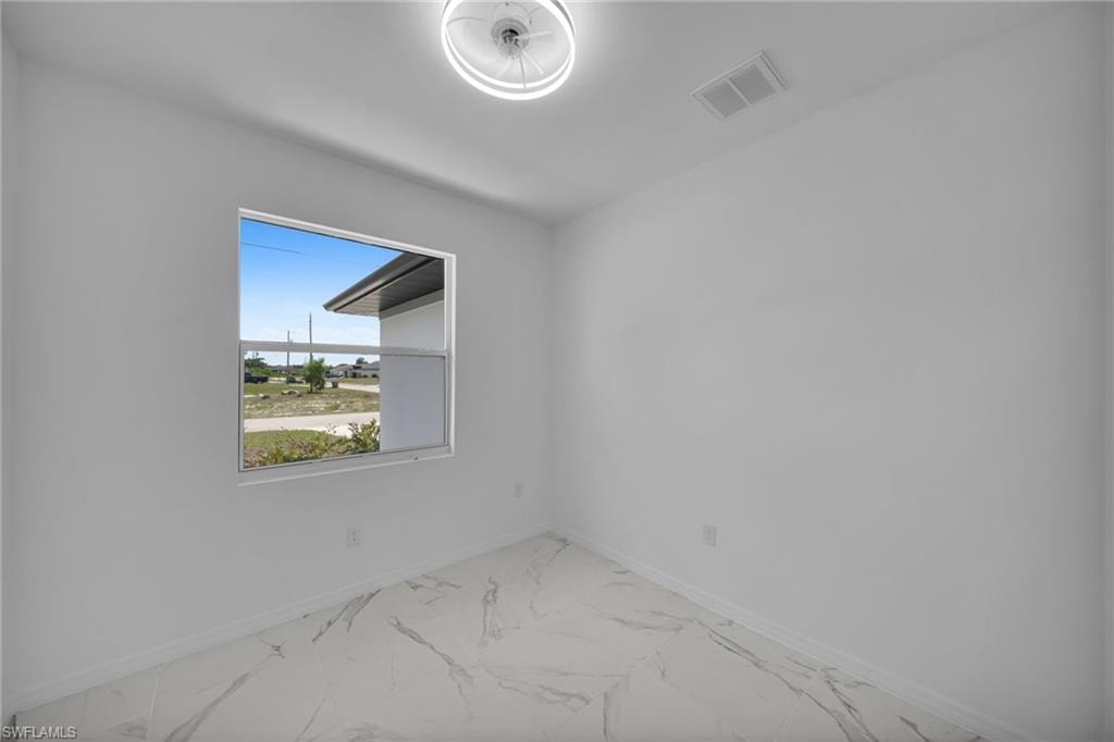 DEN! Room featuring a white-framed window, white walls, and large format marble-look tile flooring