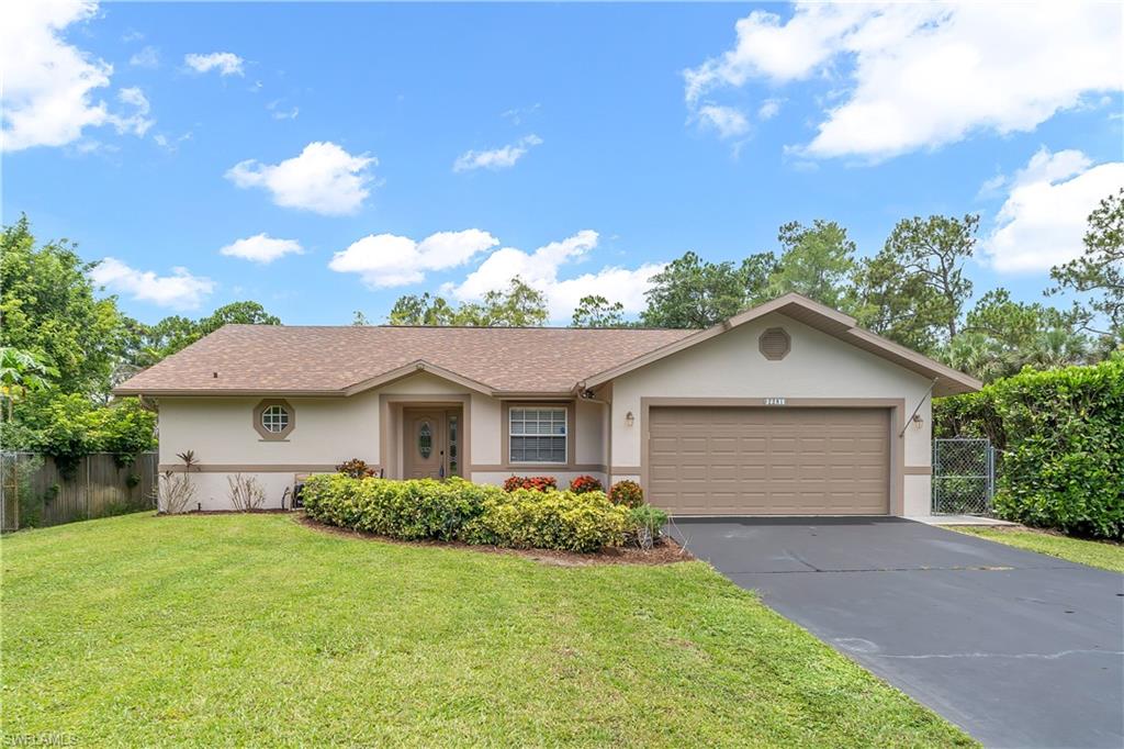 Single-story residence featuring a two-car garage, established landscaping, and a paved driveway