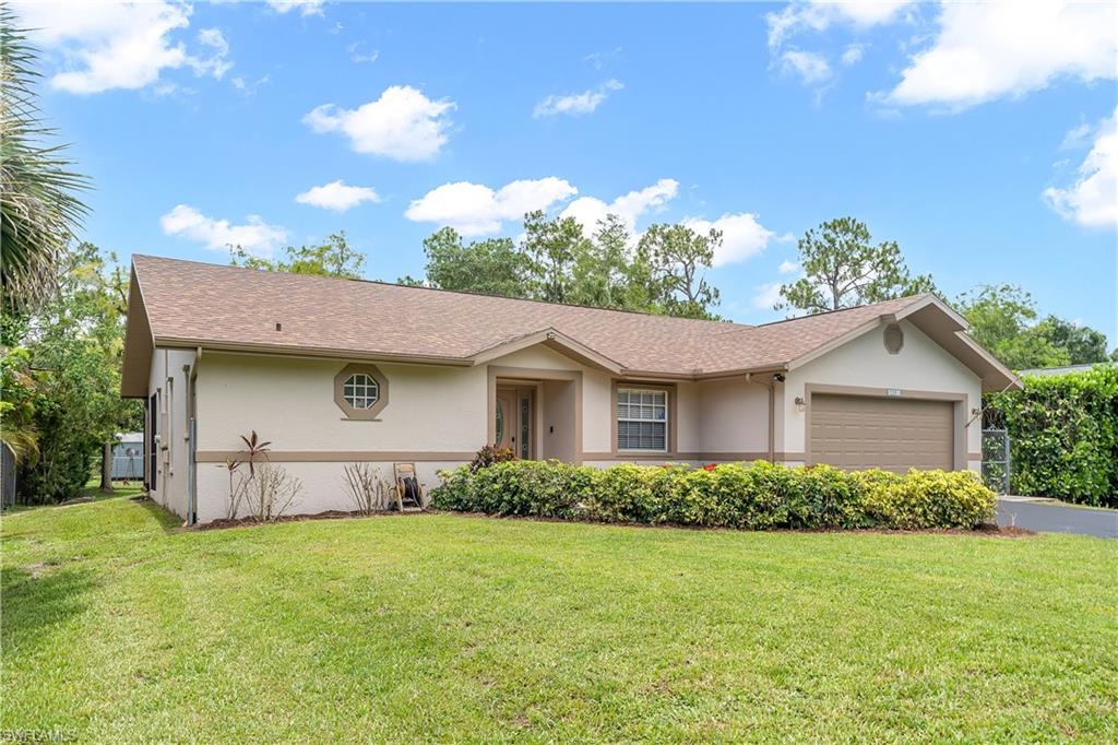 Exterior showcasing a neutral stucco finish, a brown shingle roof, a single garage door, and a decorative round window