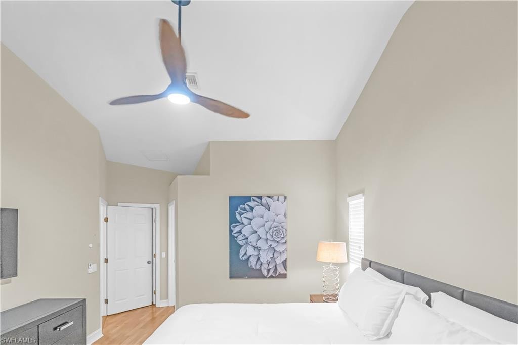 Vaulted ceiling with a modern ceiling fan, neutral wall tones, and wood-finish flooring