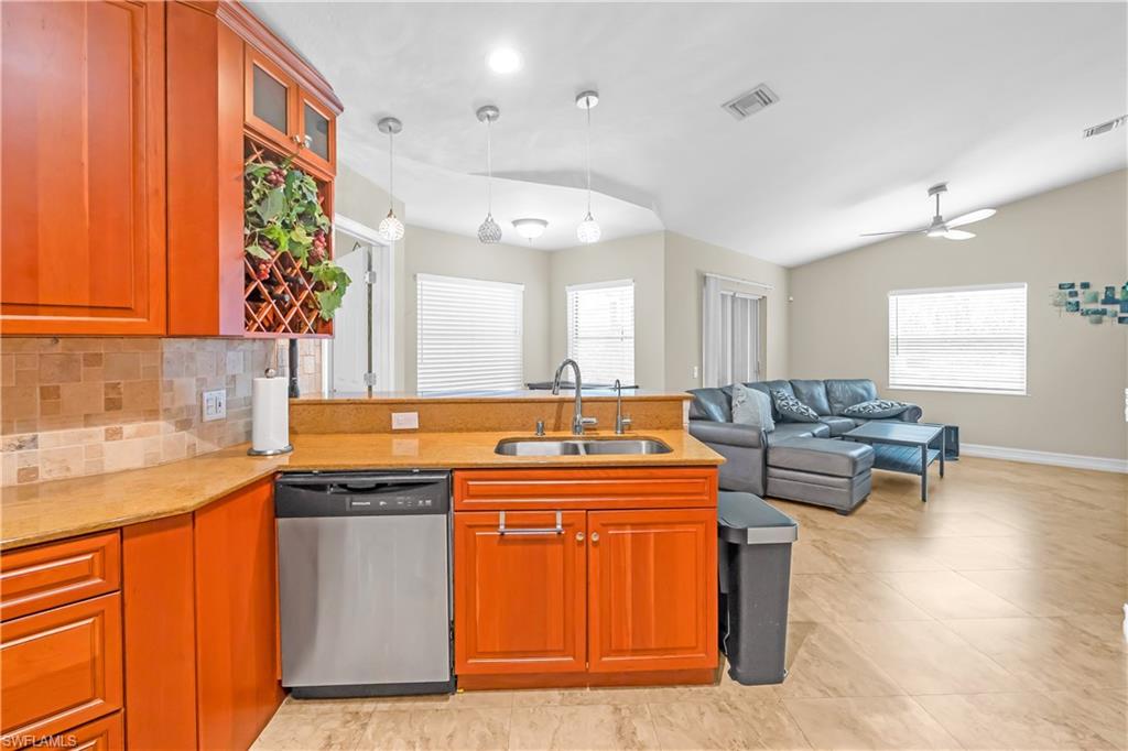 Kitchen featuring wood cabinetry, stainless steel dishwasher, and a double basin sink