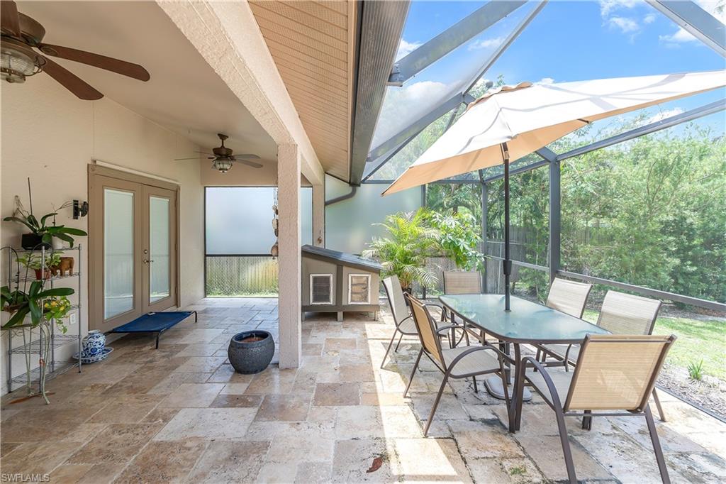 Screened-in patio with natural stone tile flooring, an exposed beam ceiling, and dual ceiling fans