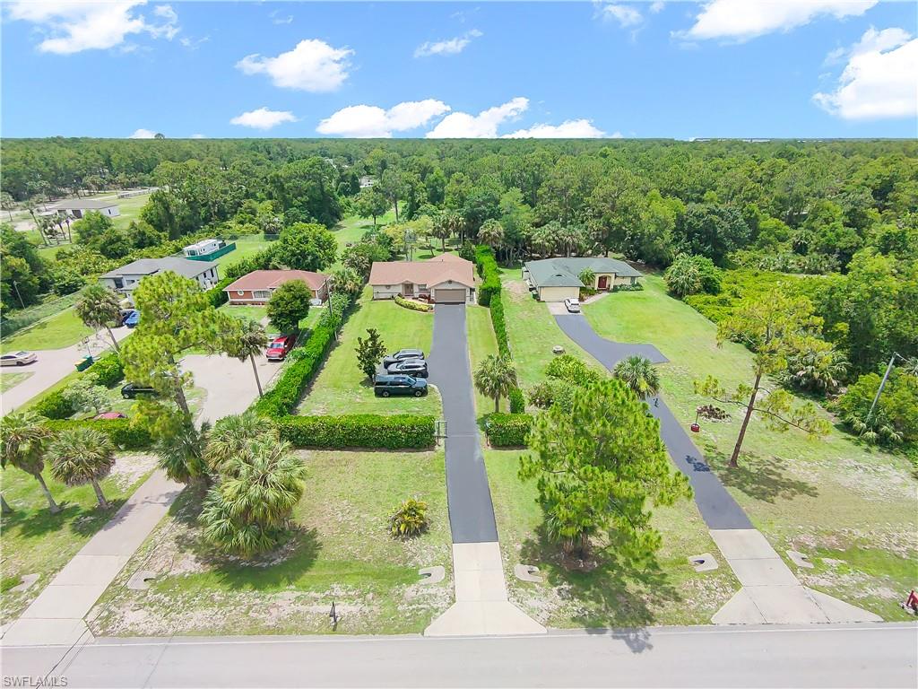 Manicured lawns with mature trees, paved driveways, and concrete sidewalks