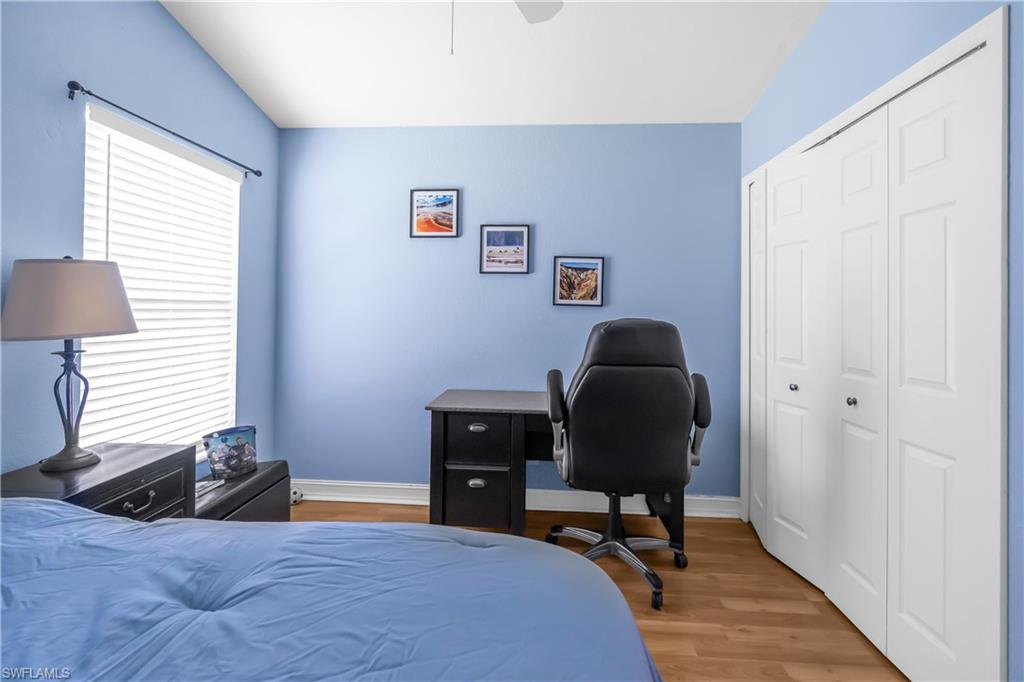 Wood-finish flooring, white bi-fold closet doors, and window with horizontal blinds
