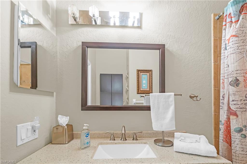 Vanity with a wood-framed mirror, undermount sink, and light-colored countertop
