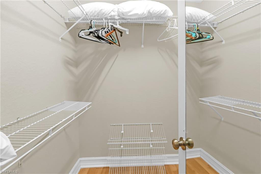 Closet with multiple wire shelving units, hanging rods, and wood-finish flooring