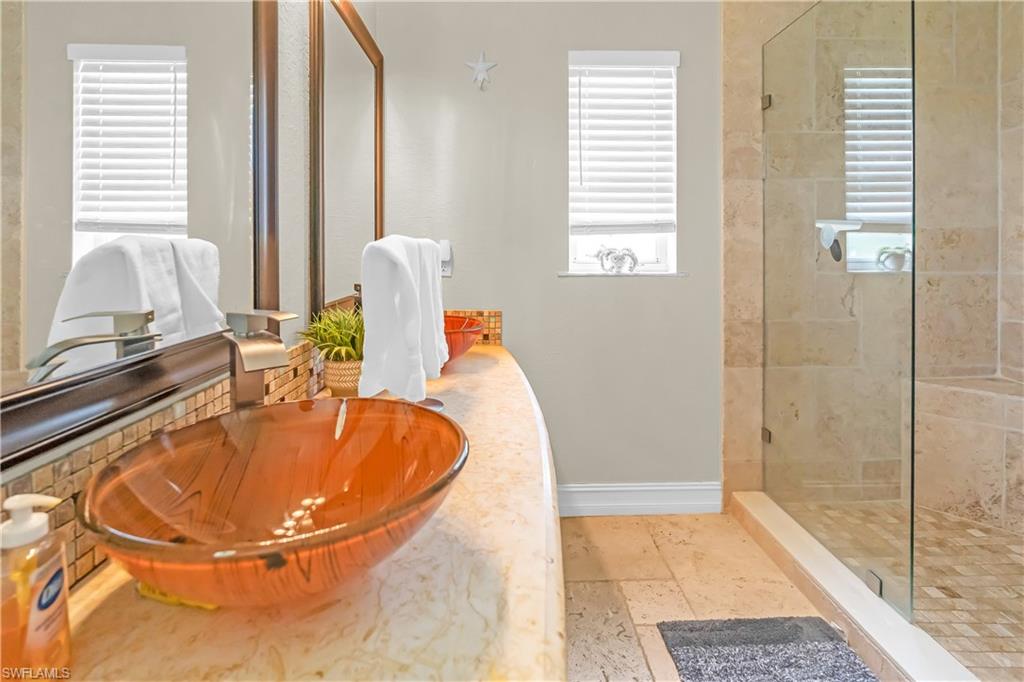 Dual vanity with a vessel sink, a tiled backsplash, and stone countertops