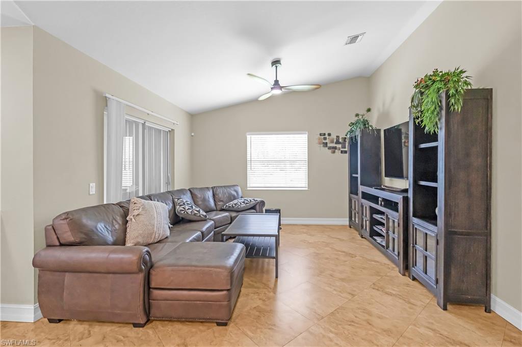Vaulted ceiling, ceiling fan, sliding glass doors, window with blinds, and tile flooring