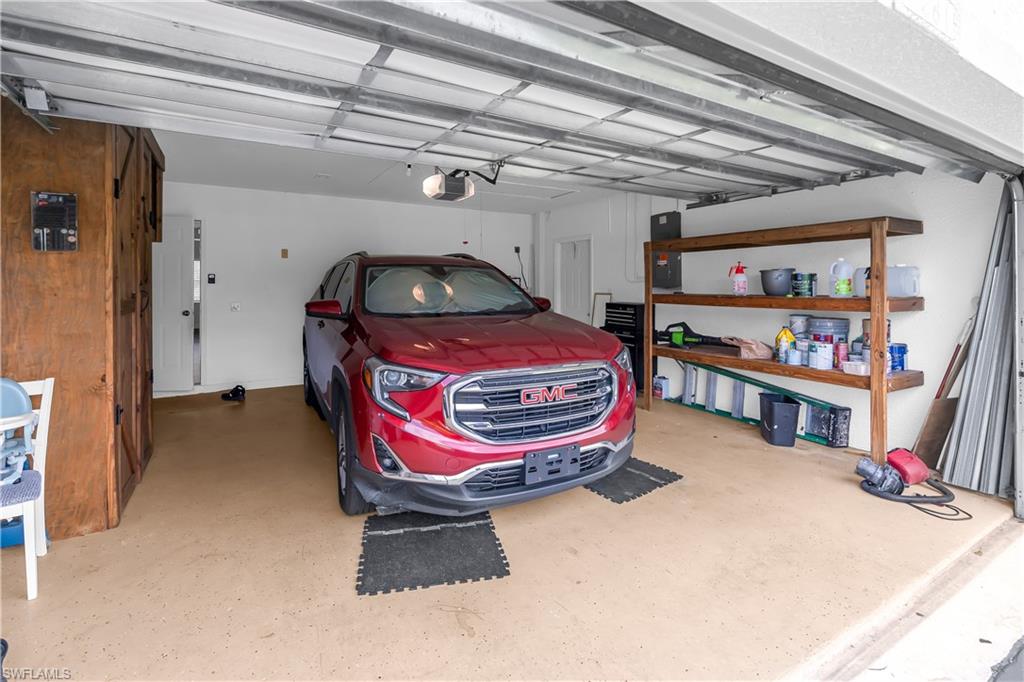Attached garage featuring an automatic door opener, light-toned epoxy flooring, and built-in wood shelving