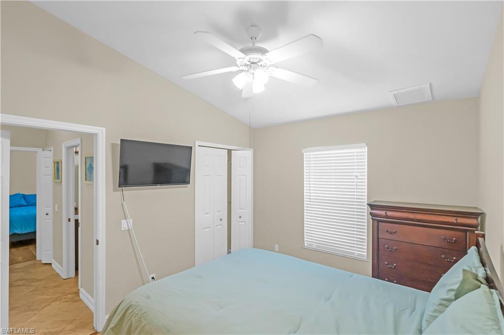 Vaulted ceiling featuring a ceiling fan, window with blinds, and bi-fold closet doors