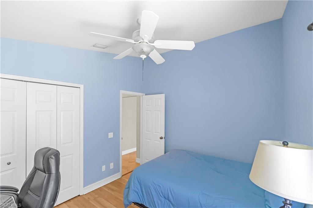 Tray ceiling with integrated ceiling fan, wood-finish flooring, white bifold closet doors, and white interior doors