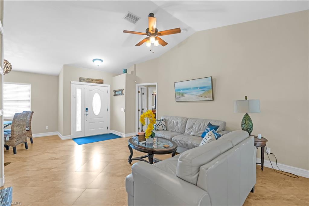 Vaulted ceilings with a ceiling fan, recessed lighting, tile flooring, and a white entry door with a sidelight and oval glass insert