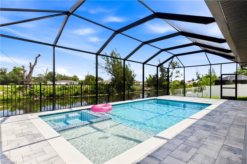 Step outside to SCREENED LANAI w/ HEATED POOL & SPA, landscape, SEAWALL & FULLY EQUIPED OUTDOOR KITCHEN