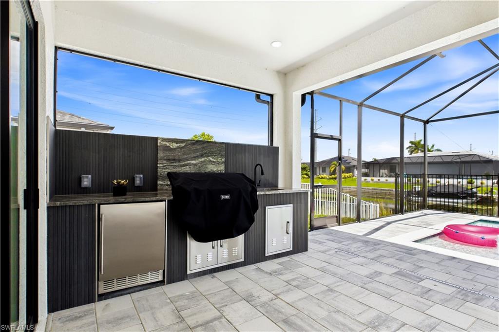 FULLY EQUIPED OUTDOOR KITCHEN w/ BUILT-IN stainless steel BBQ GRILL, SINK, BEVERAGE REFRIGERATOR, GRANITE COUNTERTOPS & MODERN BACKSPLASH!