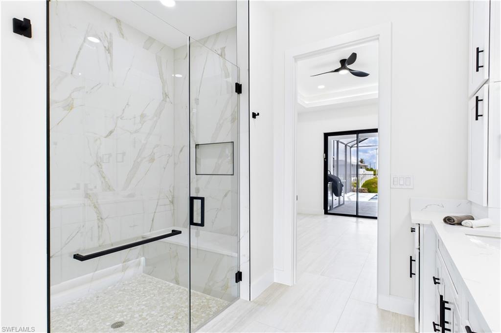LUXURIOUS PRIMARY BATHROOM w/ spacious WALK-IN GLASS SHOWER w/ floor-to-ceiling designer tile, rainfall showerhead, built-in bench & modern matte-black fixtures