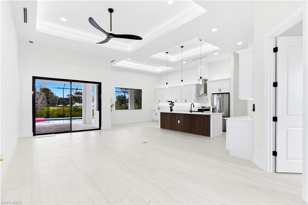 IMPACT-RESISTANT DOUBLE DOORS lead into WELCOMING LIVING ROOM w/ 14-ft VOLUME CEILING & SLIDING DOORS TO LANAI.