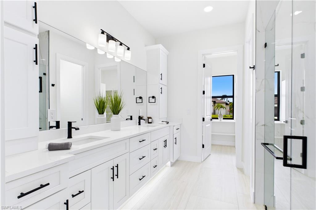 Dual sink vanity w/ quartz countertops, sleek white cabinetry & contemporary lighting complements the spa-like design