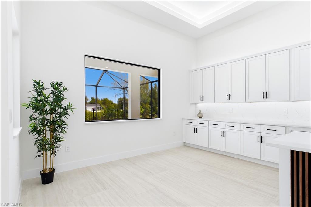 DINING ROOM features a soaring volume ceiling, recessed LED lighting & LARGE PICTURE WINDOW to screened lanai, pool/spa & waterfront.